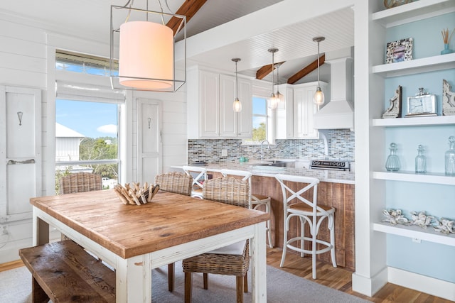 dining space featuring lofted ceiling with beams, wood finished floors, and built in features