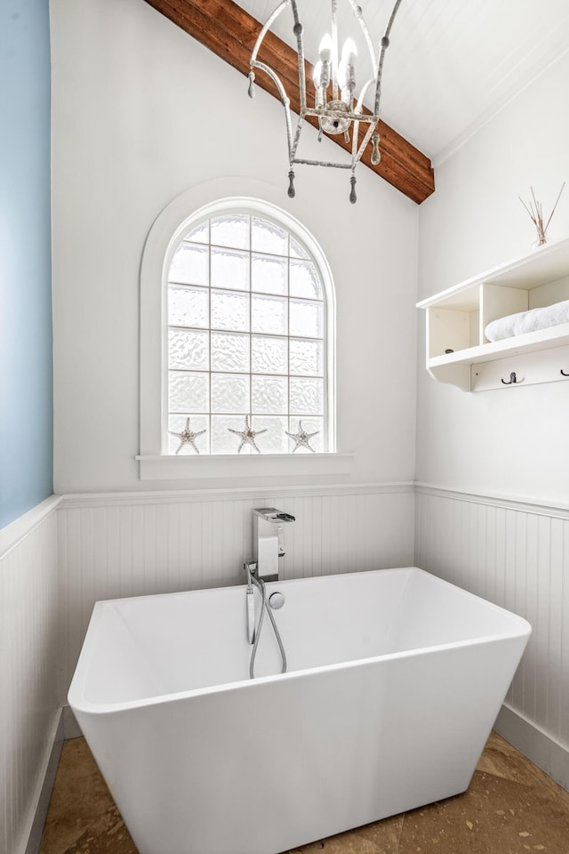 bathroom featuring a chandelier, wainscoting, a freestanding tub, and beam ceiling