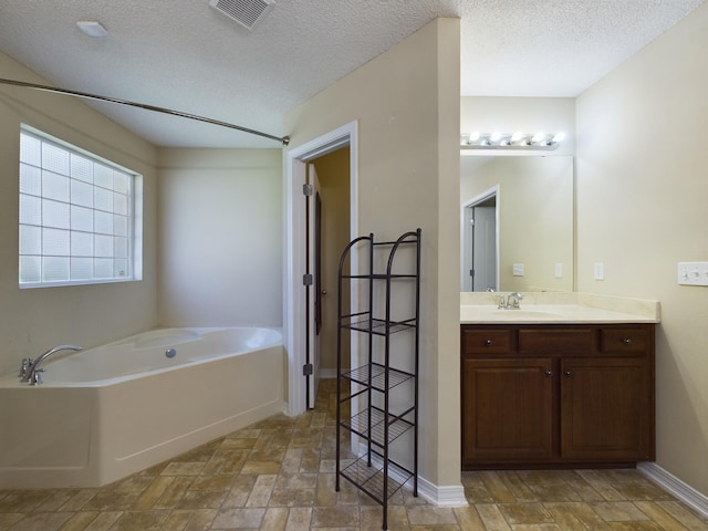 3098 Border Creek Dr, Crestview, FL 32539 - bathroom with a garden tub, visible vents, vanity, a textured ceiling, and baseboards