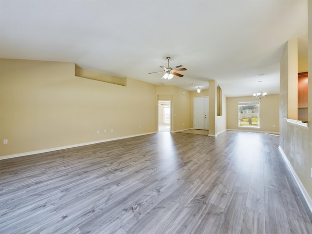 3098 Border Creek Dr, Crestview, FL 32539 - unfurnished living room featuring light wood finished floors, baseboards, vaulted ceiling, and ceiling fan with notable chandelier