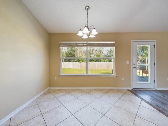 3098 Border Creek Dr, Crestview, FL 32539 - unfurnished dining area with a notable chandelier, a textured ceiling, baseboards, and light tile patterned floors