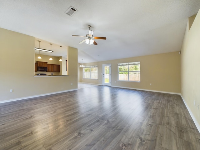 3098 Border Creek Dr, Crestview, FL 32539 - unfurnished living room featuring dark wood-type flooring, lofted ceiling, visible vents, and ceiling fan with notable chandelier