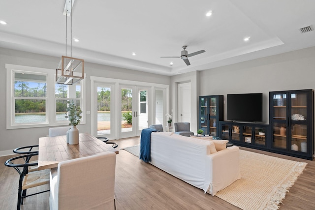 living area featuring recessed lighting, a raised ceiling, visible vents, and light wood-style floors