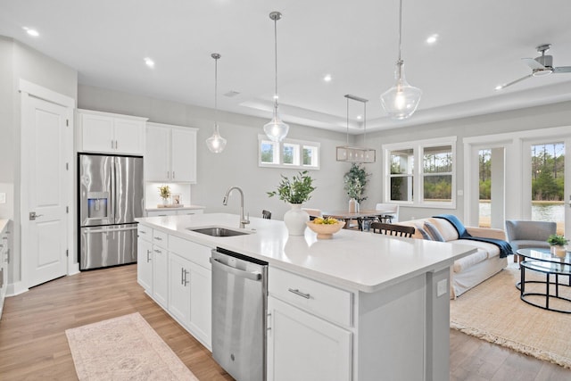 kitchen with white cabinets, stainless steel appliances, a sink, and light countertops