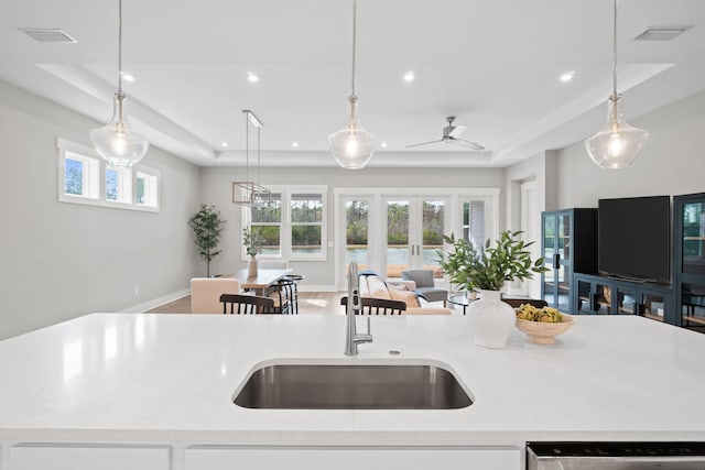 kitchen featuring decorative light fixtures, open floor plan, a sink, and light countertops