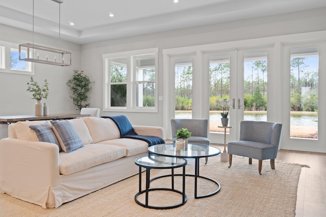 living area with recessed lighting, french doors, a water view, and plenty of natural light