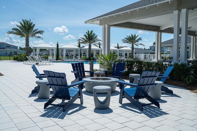 view of patio / terrace with an outdoor fire pit, a community pool, a residential view, and a gazebo