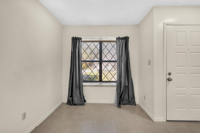 empty room featuring light tile patterned flooring and baseboards