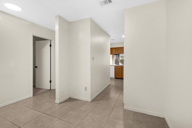 hall with visible vents, baseboards, and light tile patterned floors