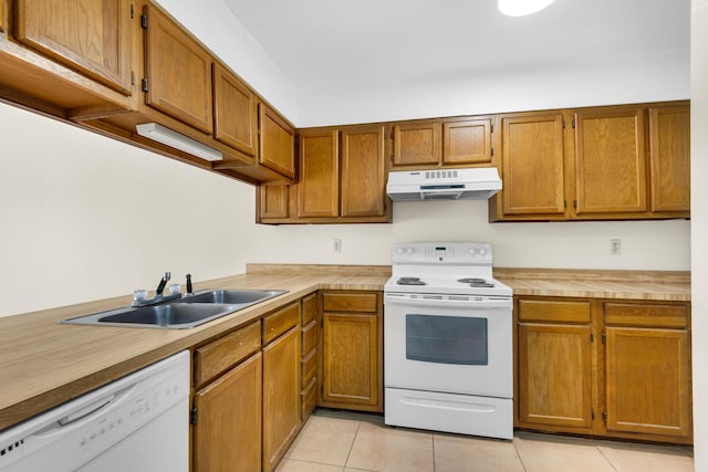 kitchen featuring light countertops, brown cabinetry, a sink, white appliances, and under cabinet range hood