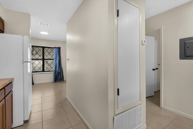 corridor with light tile patterned floors, baseboards, visible vents, and electric panel