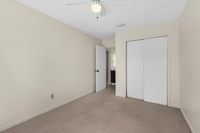 unfurnished bedroom with a closet, light colored carpet, visible vents, a ceiling fan, and baseboards