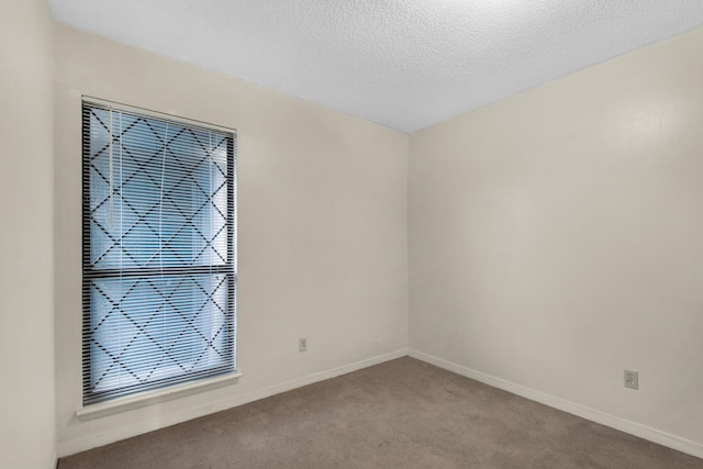 unfurnished room featuring light carpet, a textured ceiling, and baseboards