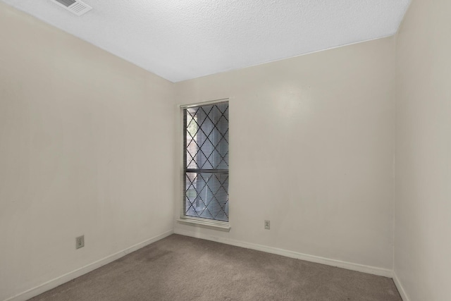 unfurnished room with carpet flooring, visible vents, baseboards, and a textured ceiling