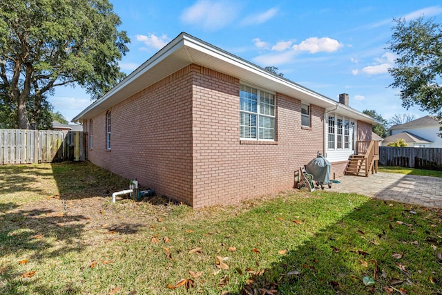 view of home's exterior with a patio, brick siding, a lawn, and a fenced backyard