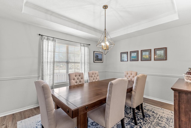 dining space with ornamental molding, a tray ceiling, and wood finished floors