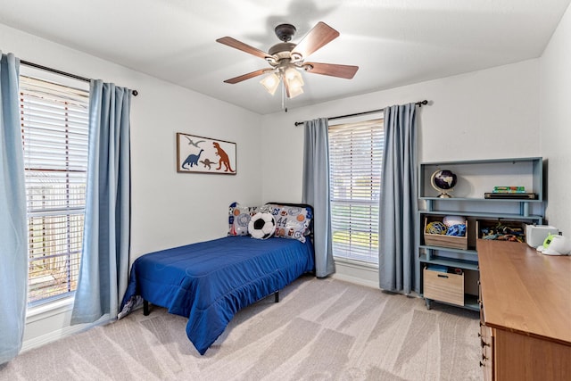 bedroom featuring light carpet, ceiling fan, and baseboards