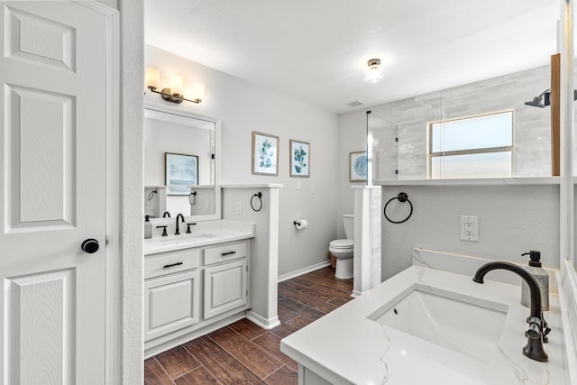 bathroom featuring wood finish floors, two vanities, a sink, and toilet