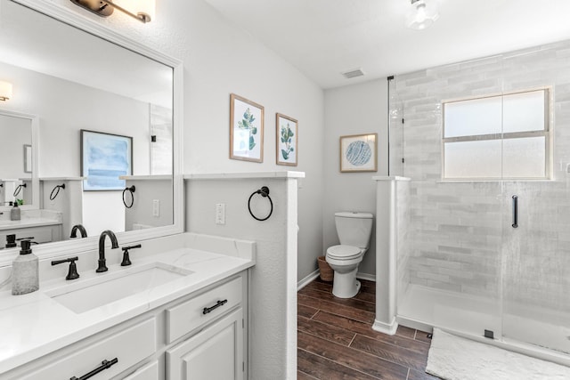 bathroom with visible vents, toilet, vanity, a shower stall, and wood finish floors