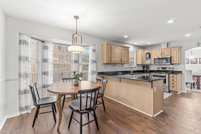 kitchen featuring stainless steel appliances, a sink, a peninsula, and light brown cabinetry