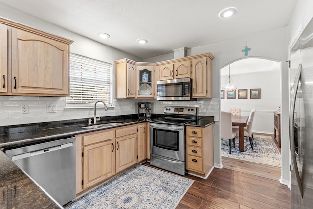 kitchen with light brown cabinets, appliances with stainless steel finishes, a sink, and dark wood-style floors