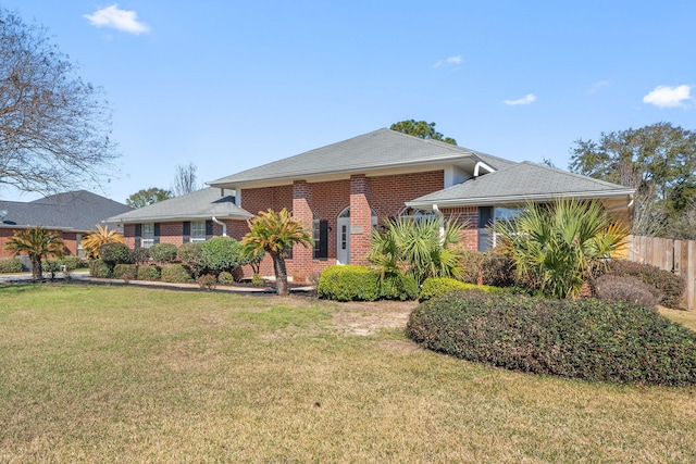 view of front of house featuring brick siding, fence, and a front lawn