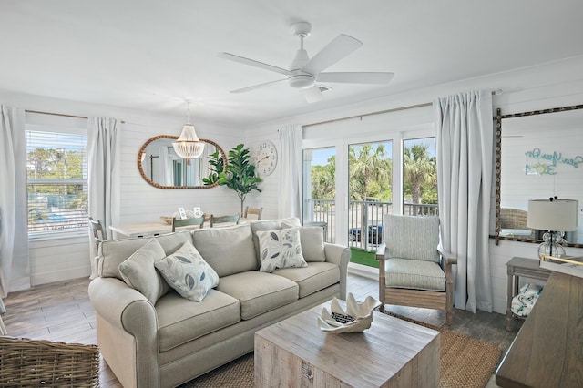 living area with dark wood-type flooring, plenty of natural light, wood walls, and ceiling fan