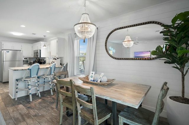 dining area featuring a toaster, recessed lighting, wooden walls, dark wood-style flooring, and an inviting chandelier