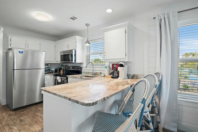 kitchen featuring stainless steel appliances, a peninsula, visible vents, white cabinetry, and pendant lighting