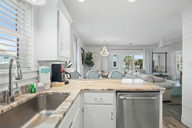 kitchen featuring dark wood-style floors, stainless steel dishwasher, open floor plan, white cabinets, and a sink