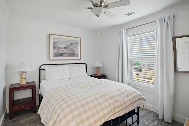 bedroom featuring baseboards, visible vents, wood finished floors, and ornamental molding