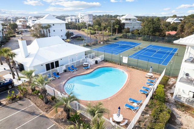 pool featuring a tennis court, a residential view, and fence