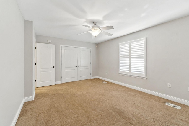 unfurnished bedroom with visible vents, a ceiling fan, a closet, baseboards, and light colored carpet