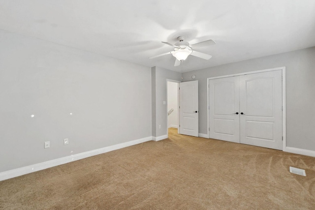 unfurnished bedroom with visible vents, light carpet, a ceiling fan, a closet, and baseboards