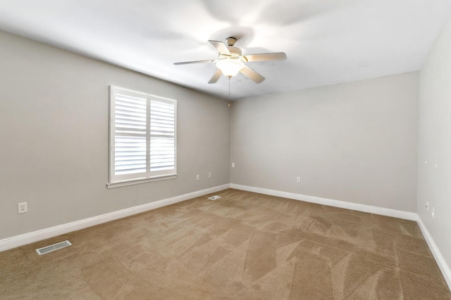 carpeted empty room featuring visible vents, baseboards, and ceiling fan