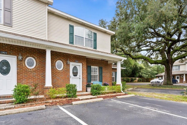 view of front of home with brick siding and uncovered parking