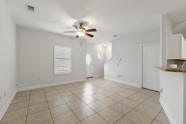 spare room featuring light tile patterned flooring, visible vents, baseboards, and ceiling fan