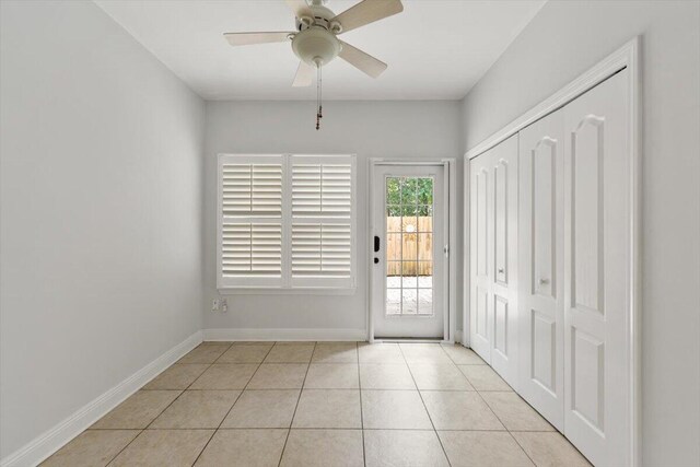 doorway to outside with light tile patterned floors, a ceiling fan, and baseboards