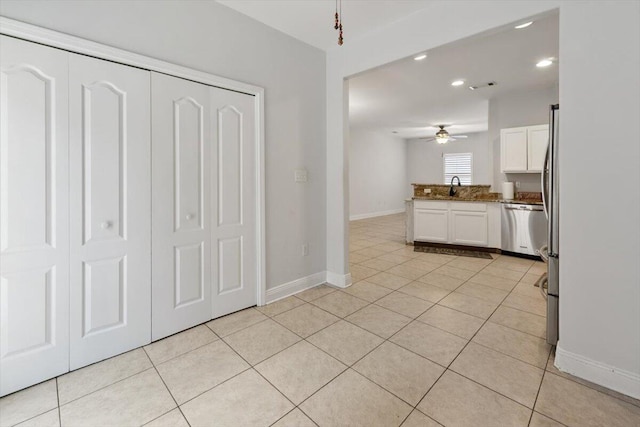 kitchen featuring stainless steel dishwasher, a peninsula, white cabinets, and light tile patterned floors