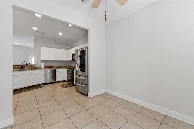 kitchen with dark stone countertops, light tile patterned floors, baseboards, stainless steel appliances, and white cabinetry