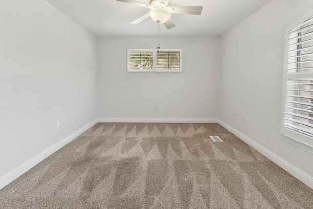 carpeted spare room with visible vents, a ceiling fan, and baseboards