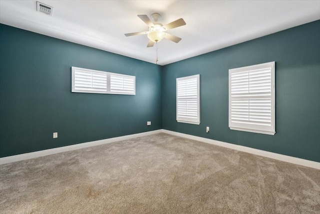 empty room with visible vents, carpet floors, baseboards, and a ceiling fan