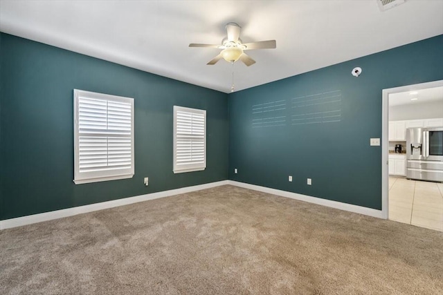 empty room with light carpet, visible vents, baseboards, and ceiling fan