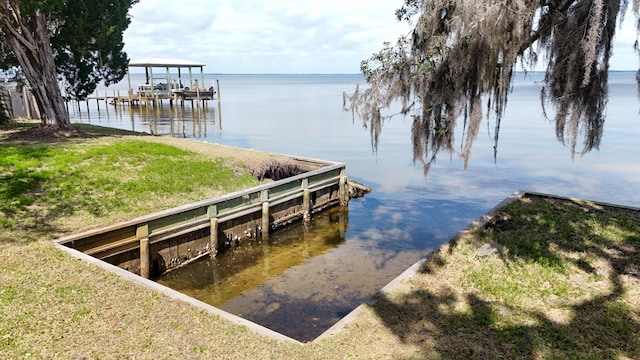 view of dock with a water view and a yard