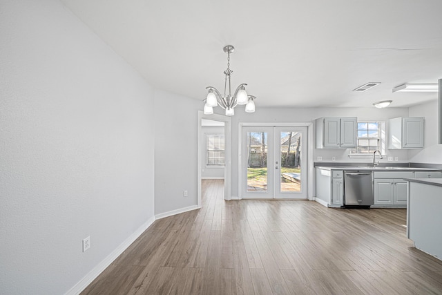 unfurnished dining area with light wood-type flooring, baseboards, visible vents, and a sink