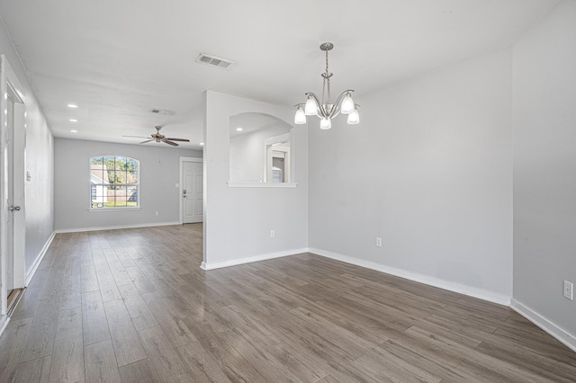 spare room featuring arched walkways, recessed lighting, wood finished floors, visible vents, and baseboards