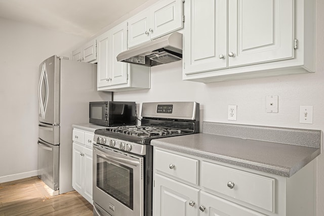 kitchen featuring black microwave, under cabinet range hood, white cabinets, light countertops, and gas stove