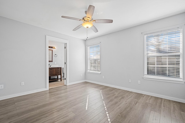 spare room with ceiling fan, light wood-type flooring, and baseboards