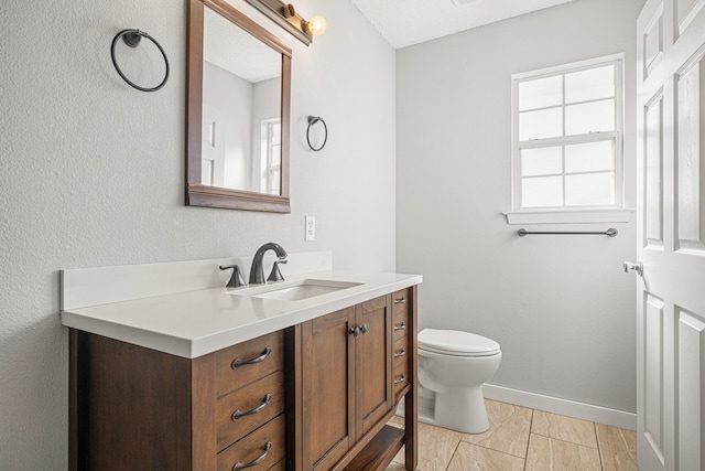 bathroom with baseboards, vanity, and toilet