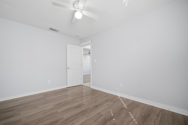 empty room featuring visible vents, ceiling fan, a textured ceiling, wood finished floors, and baseboards